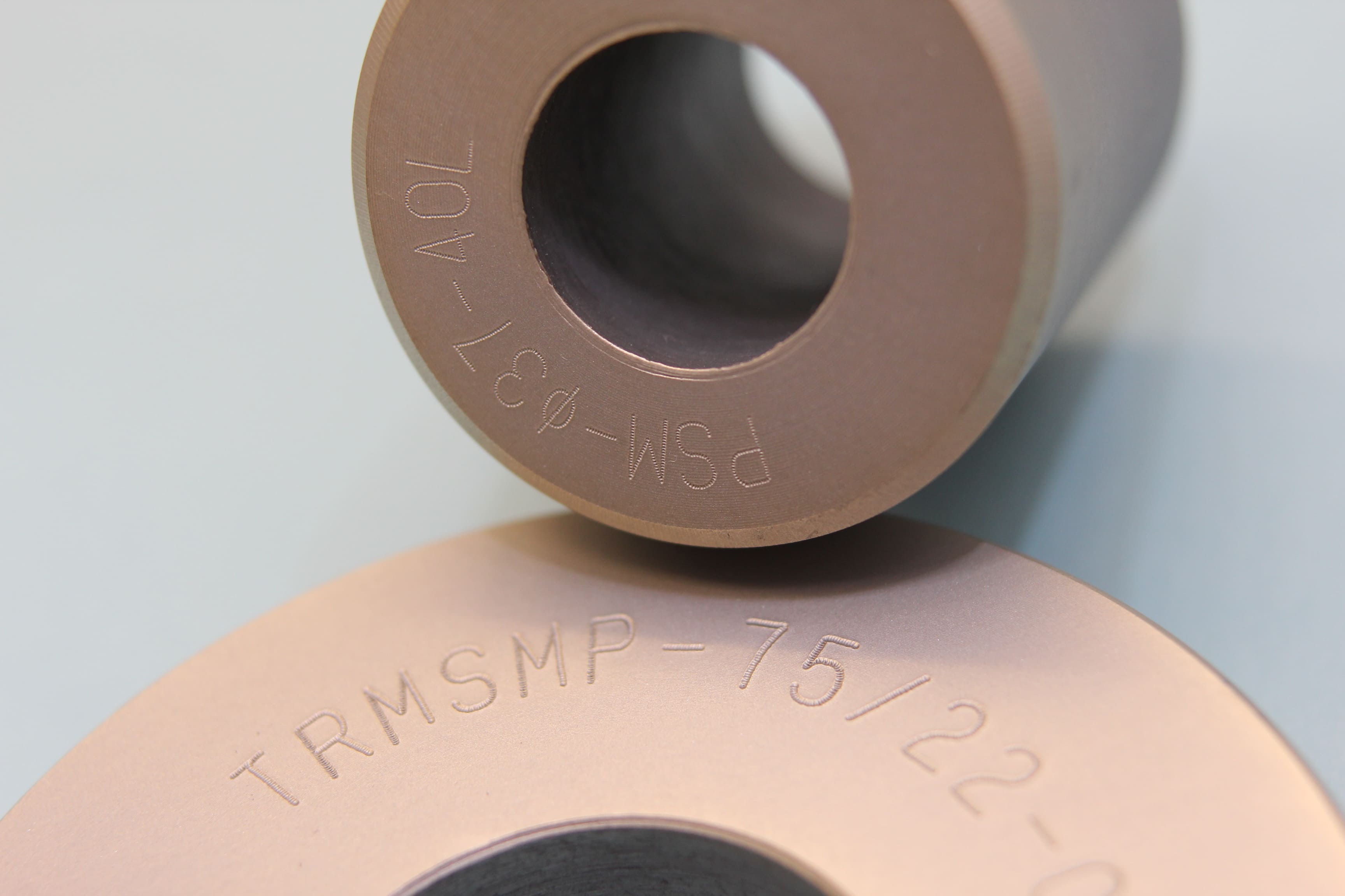 Image of Engraving on two Donut-shaped Parts (arc marking) with text 'TRMSMP-75/22-' for one and 'PSM-Ø37-40L' for the other.