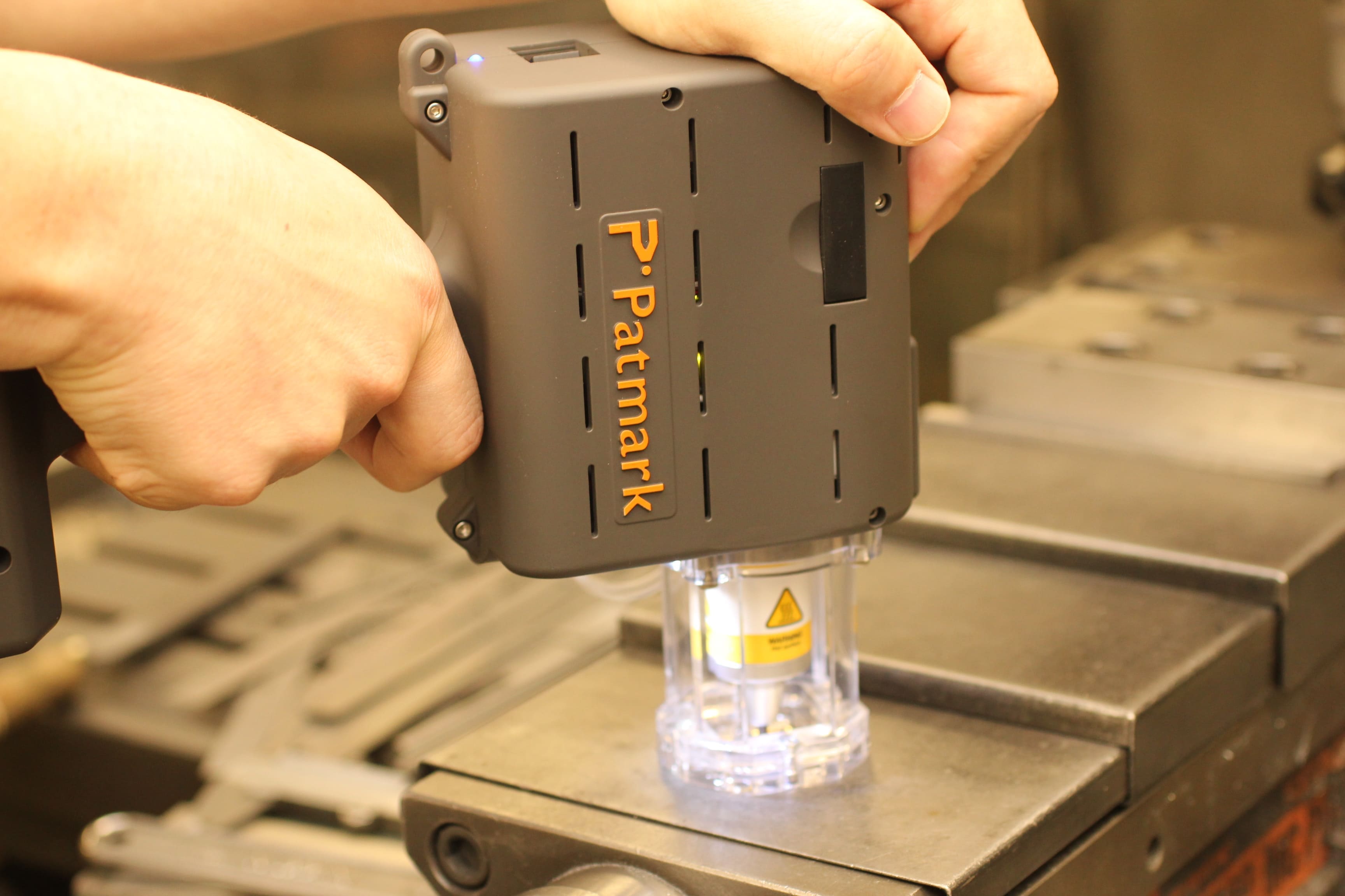 Image of a person holding and using Patmark-mini for engraving