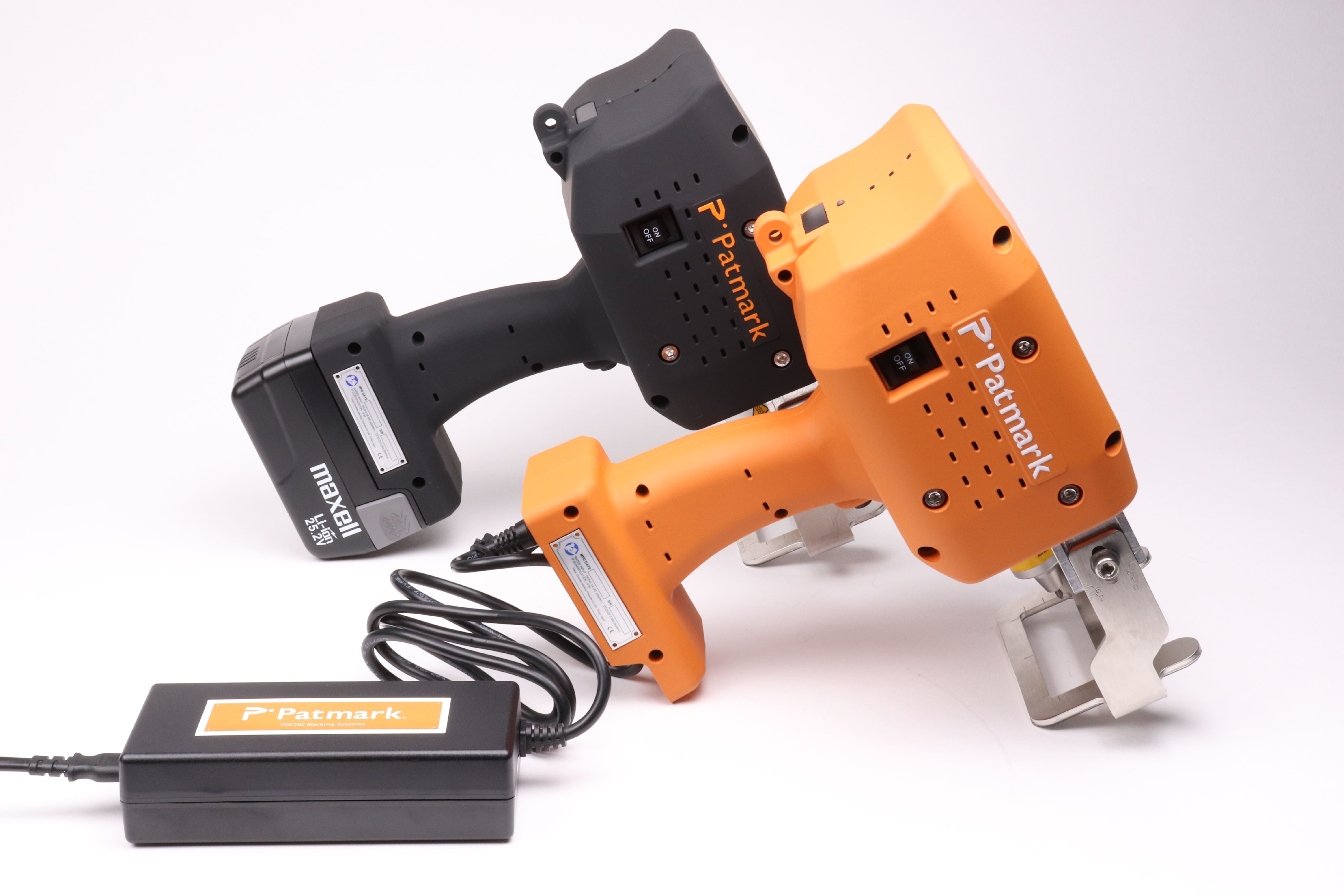 Image of two Patmark-plus units from the Patmark series, one in orange and one in black, placed side by side. The black one is equipped with an adapter.