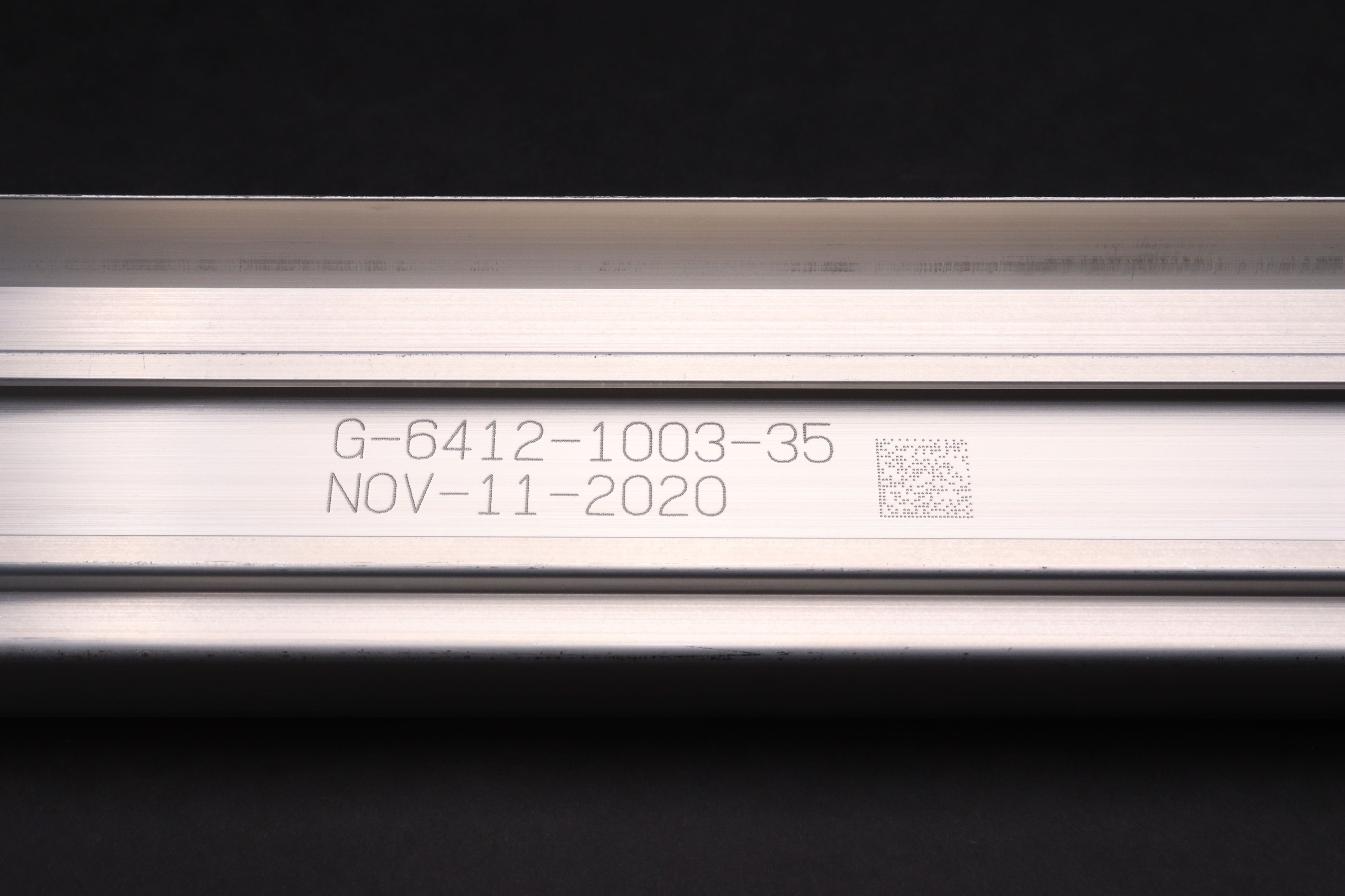 Image of an aluminum profile engraved with text, numbers, and a QR code that reads 'G-6412-1003-35 NOV-11-2020'.